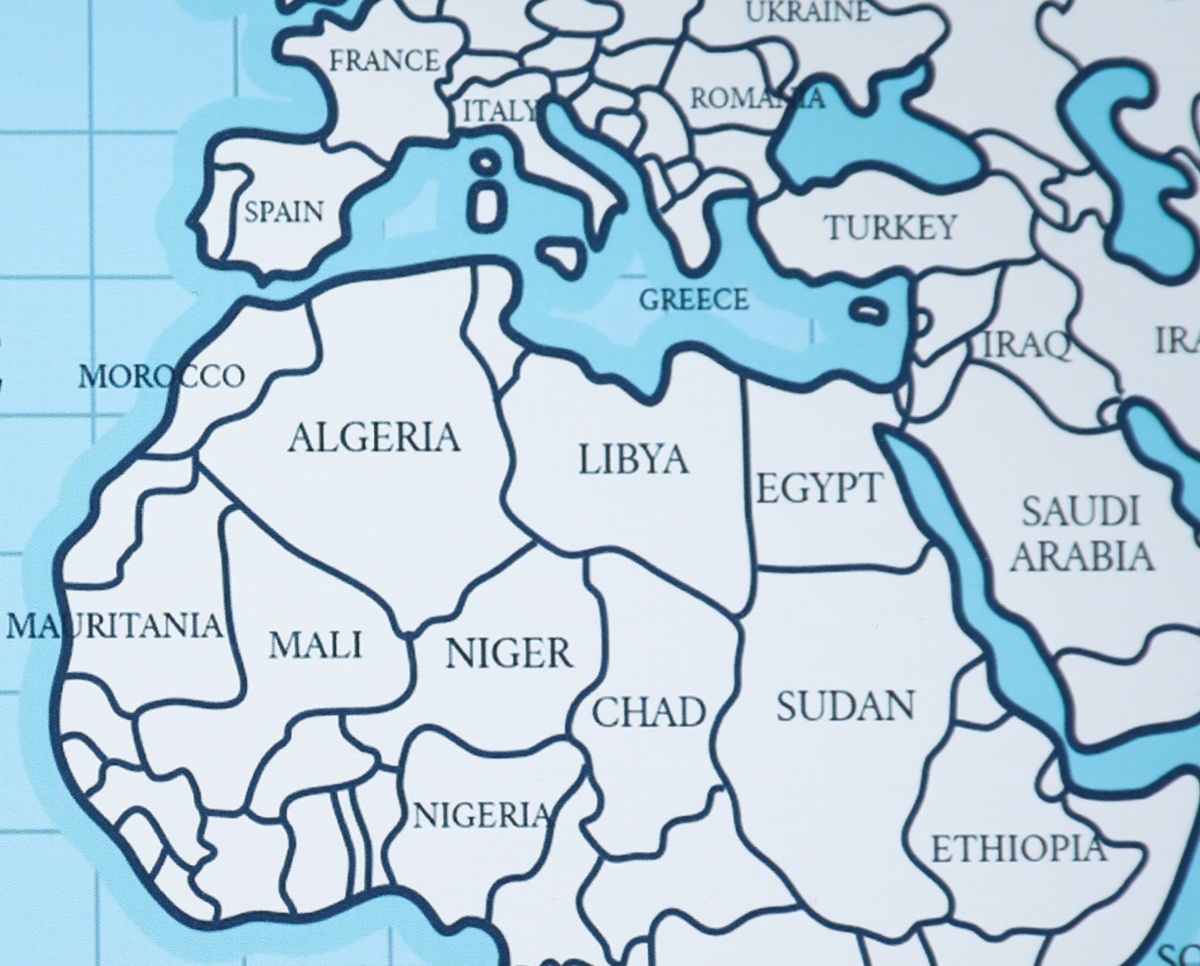 Illustrated political map of North Africa and southern Europe with country borders and blue water outlines, showing Algeria, Libya, Egypt, Morocco, Greece, Italy, Spain, and surrounding nations.