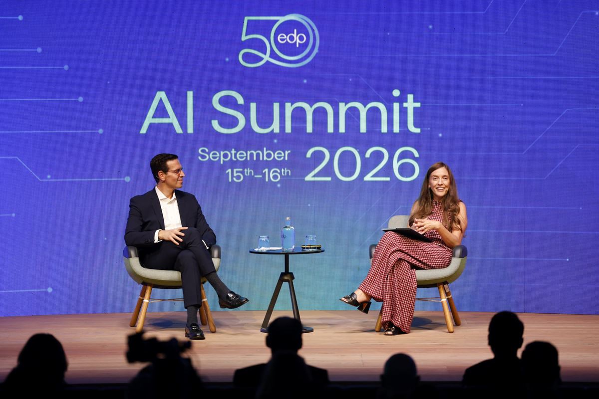 Two speakers sit on stage at an AI Summit 2026 panel, blue backdrop with 'AI Summit 2026' branding and dates September 15–16, 2026.
